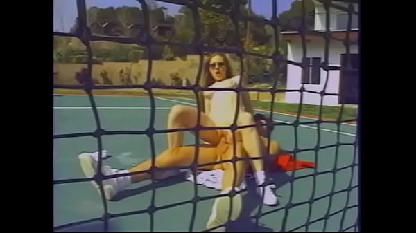 Une brune sexy avec de beaux seins aime baiser sur le court de tennis avec un entraîneur excité et lui suce la bite
